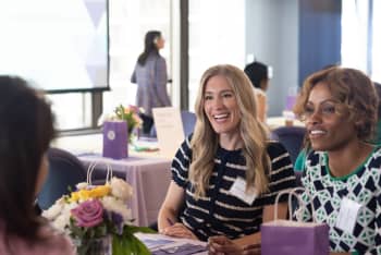 Two people talking and smiling with a third person who is out of view