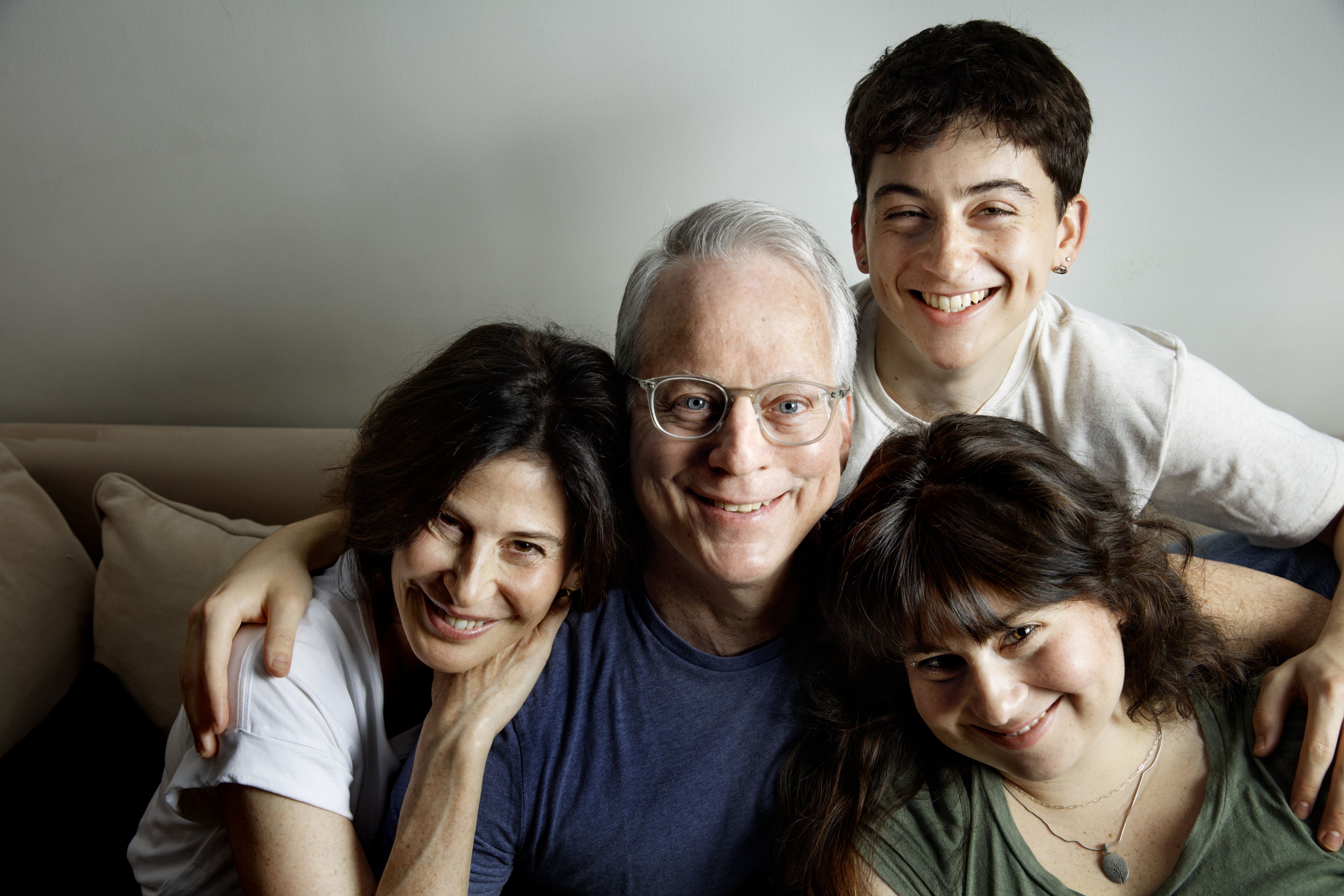 A family of four sits together embracing and smiling