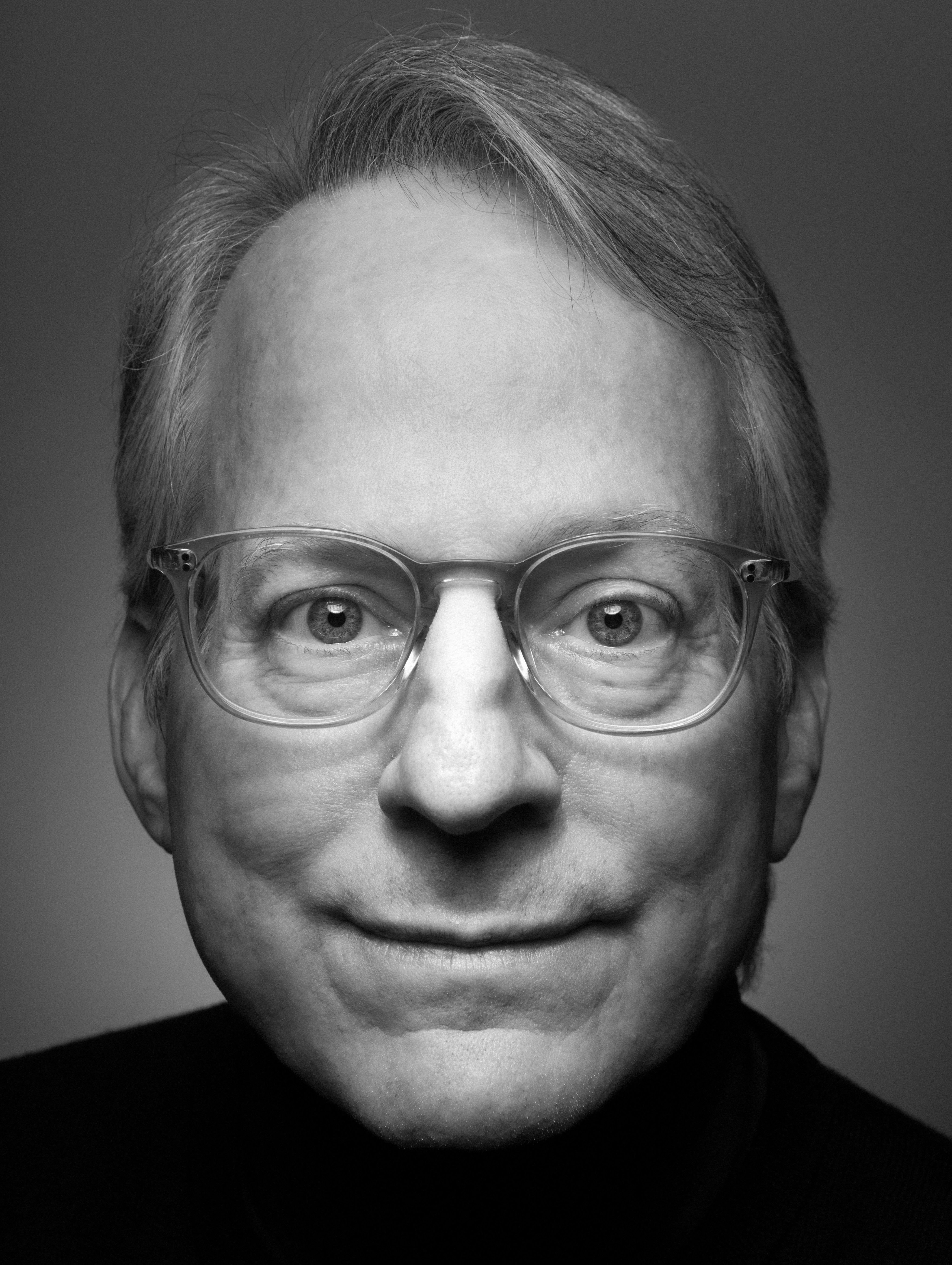 Headshot of Jonathan Gluck where he's wearing clear-framed glasses, looking at the reader and slightly smiling