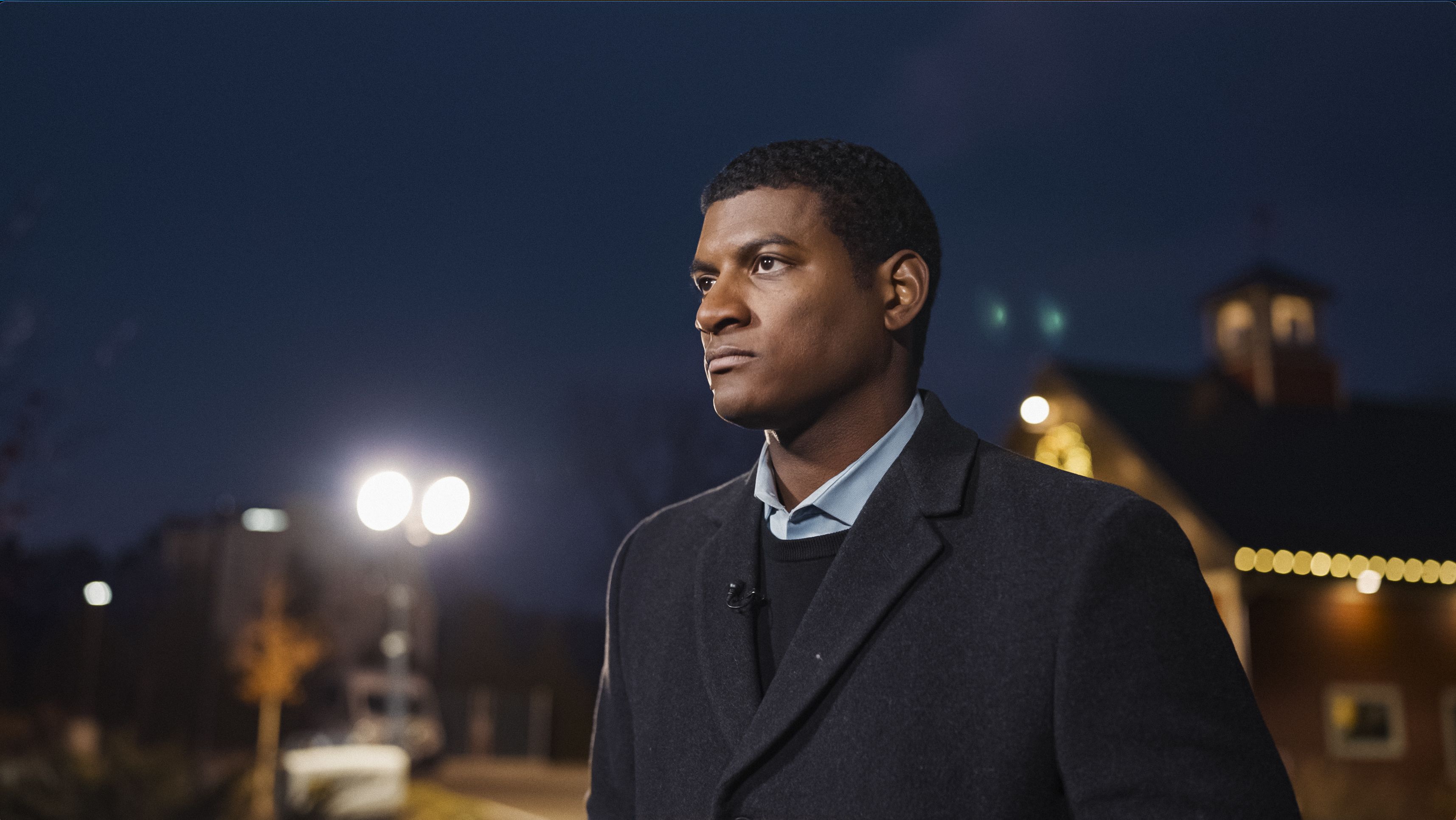 Omar Jimenez stands looking into the distance at nightfall